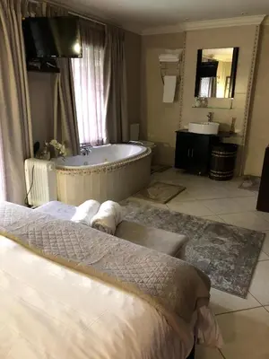 a bathroom with a tub and a bed and a sink at Annie's Place in Kempton Park