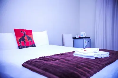 a bed with a purple blanket on top of it at Mmakosha Lodge in Pretoria