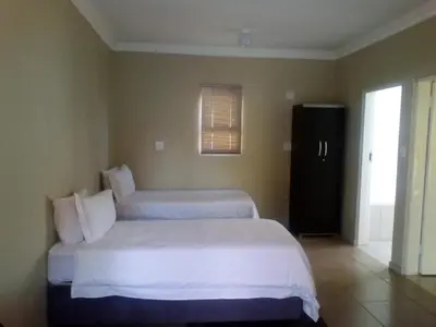 a hotel room with two beds and a window at Mmakosha Lodge in Pretoria