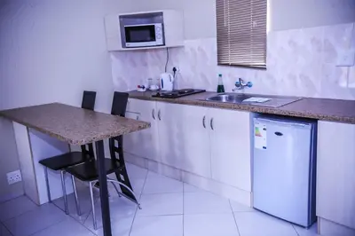 a kitchen with a counter and a sink and a refrigerator at Mmakosha Lodge in Pretoria