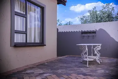 a white table sitting outside of a building with a window at Mmakosha Lodge in Pretoria