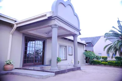 a white house with a porch and a door at Mmakosha Lodge in Pretoria