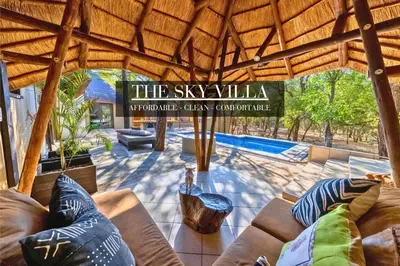 a living room with couches and a swimming pool at African Sky Villas in Marloth Park
