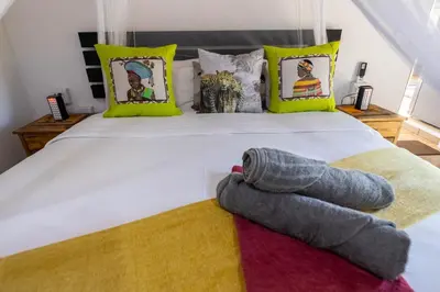 a bedroom with a large white bed with yellow pillows at African Sky Villas in Marloth Park