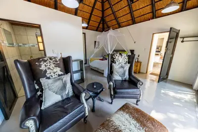 a living room with two chairs and a bed at African Sky Villas in Marloth Park