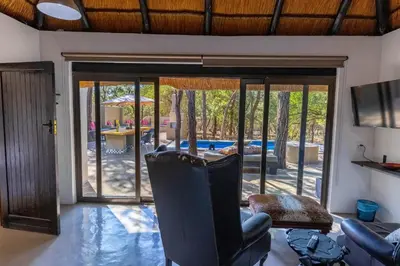 a living room with a chair and a sliding glass door at African Sky Villas in Marloth Park