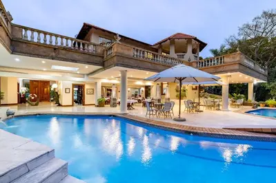 a house with a swimming pool with an umbrella at Christies at 32 on Russell in Nelspruit