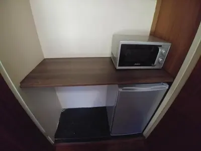 a microwave sitting on a wooden shelf in a room at 22 on Nicol in Secunda