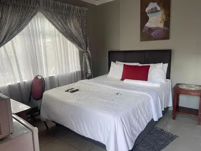 a bedroom with a large white bed with a red pillow at Dreamwood Guest House in Nelspruit