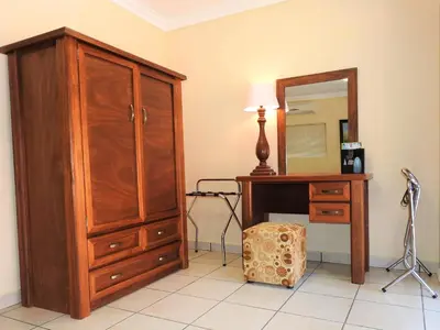 a bedroom with a wooden dresser and a mirror at Ubuntu Bed and Breakfast in Marloth Park
