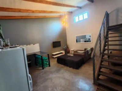 a living room with a couch and a stair case at Arend Cottage in Nelspruit