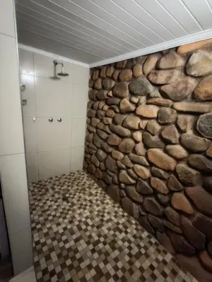 a stone wall in a bathroom with a shower at Arend Cottage in Nelspruit