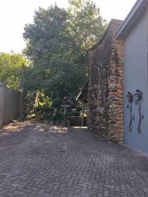 a brick driveway next to a building with a tree at Arend Cottage in Nelspruit