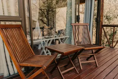 two wooden chairs and a table on a porch at Panzi Lodge in Guernsey Nature Reserve