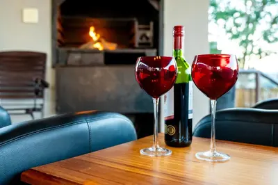 two wine glasses sitting on a table with a bottle of wine at 7th Hole Golf Lodge in Modimolle