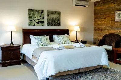 a bedroom with a large bed with two towels on it at 7th Hole Golf Lodge in Modimolle