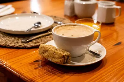a cup of coffee and a piece of bread on a table at 7th Hole Golf Lodge in Modimolle