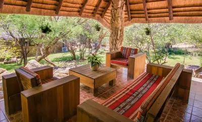 a porch with a bench and a table and chairs at Hasekamp Hospitality in Hoedspruit