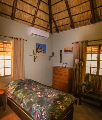 a bedroom with a bed and a dresser and windows at Hasekamp Hospitality in Hoedspruit