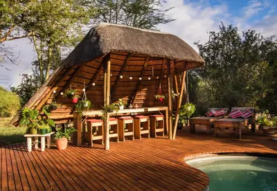 a pavilion with a table and chairs next to a pool at Hasekamp Hospitality in Hoedspruit