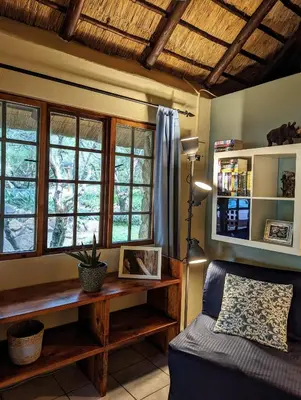 a bedroom with a bed and windows and a table at Hasekamp Hospitality in Hoedspruit