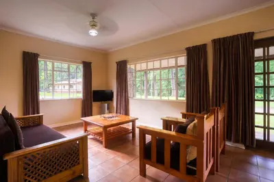 a living room with a couch and a table and windows at Merry Pebbles Resort in Sabie
