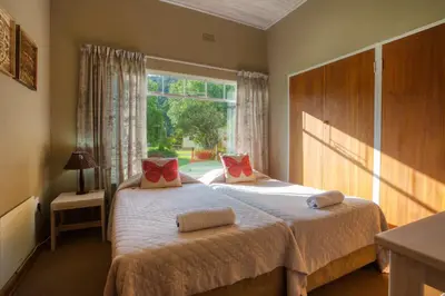 a bedroom with two beds and a large window at Merry Pebbles Resort in Sabie