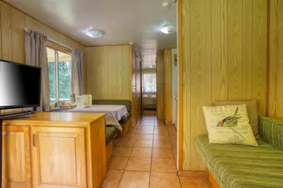 a room with a bed and a tv and a couch at Merry Pebbles Resort in Sabie