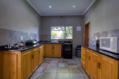a large kitchen with wooden cabinets and a microwave at Merry Pebbles Resort in Sabie