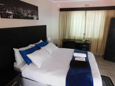 a bedroom with a large bed with blue and white pillows at Savannah Guest House in Polokwane