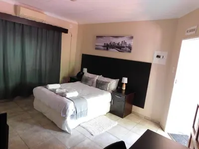 a bedroom with a large bed with a black headboard at Savannah Guest House in Polokwane
