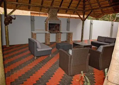 a patio with wicker chairs and a fireplace at Savannah Guest House in Polokwane