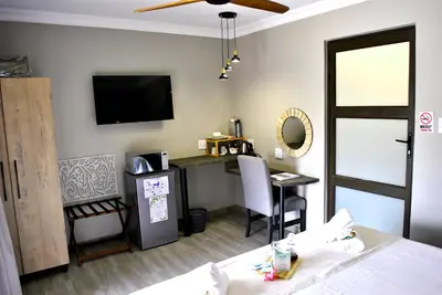 a room with a bed and a desk and a television at Christie's Inn in Tzaneen