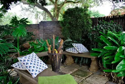 a garden with a bench with pillows and a plant at Christie's Inn in Tzaneen
