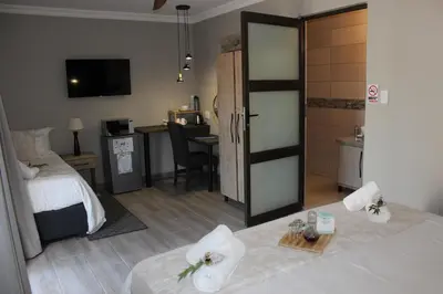 a hotel room with a bedroom with a bed and a desk at Christie's Inn in Tzaneen