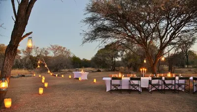 a group of tables with candles in a field at Safari Plains in Mabula