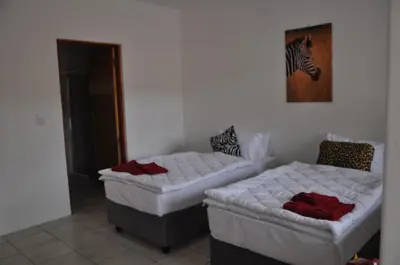 a room with two beds and a picture of a zebra at Hazyview Buffalo Game Lodge in Hazyview