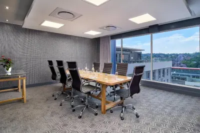 a conference room with a wooden table and chairs at Protea Hotel by Marriott Pretoria Loftus Park in Pretoria