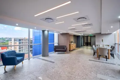 an office lobby with chairs and a table and large windows at Protea Hotel by Marriott Pretoria Loftus Park in Pretoria