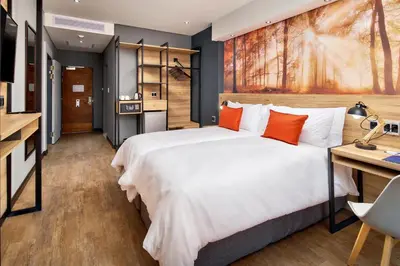 a bedroom with a large white bed with orange pillows at Protea Hotel by Marriott Pretoria Loftus Park in Pretoria