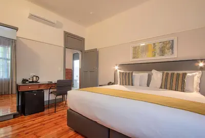a bedroom with a large bed and a desk at THE Pretoria Hotel in Pretoria