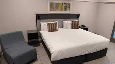 a bedroom with a large bed and a chair at THE Pretoria Hotel in Pretoria