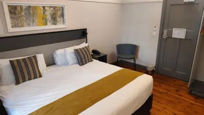 a bedroom with a bed and a chair at THE Pretoria Hotel in Pretoria