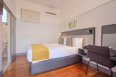 a bedroom with a bed with a desk and a chair at THE Pretoria Hotel in Pretoria