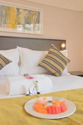 a plate of fruit sitting on top of a bed at THE Pretoria Hotel in Pretoria