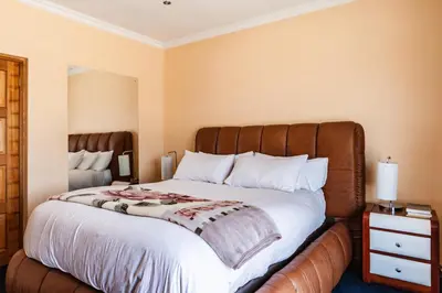 a bedroom with a large bed with a wooden headboard at Alimama Spaces: Manson Mansion in Randjesfontein