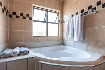 a large white tub in a bathroom with a window at Alimama Spaces: Manson Mansion in Randjesfontein