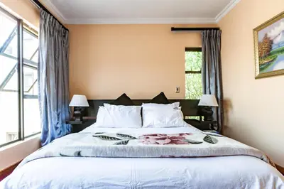 a bedroom with a large bed with white pillows at Alimama Spaces: Manson Mansion in Randjesfontein