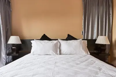 a bedroom with a bed with white sheets and two lamps at Alimama Spaces: Manson Mansion in Randjesfontein