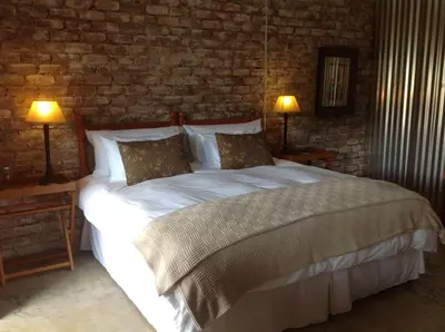 a bedroom with a large white bed with two lamps at The Red Barn in Weimershoek